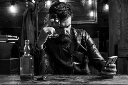 有胡子的男人穿着西装,喝着威士忌白兰地或白兰地.侍者品尝酒精饮料.