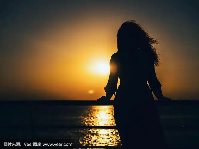 在日落的海滩上,快乐的女人穿着夏装的剪影.自然光和色彩