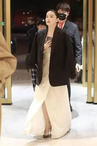 近日,阚清子现身某酒店,她身穿白色礼服披着黑西装外套御寒,用手捂着