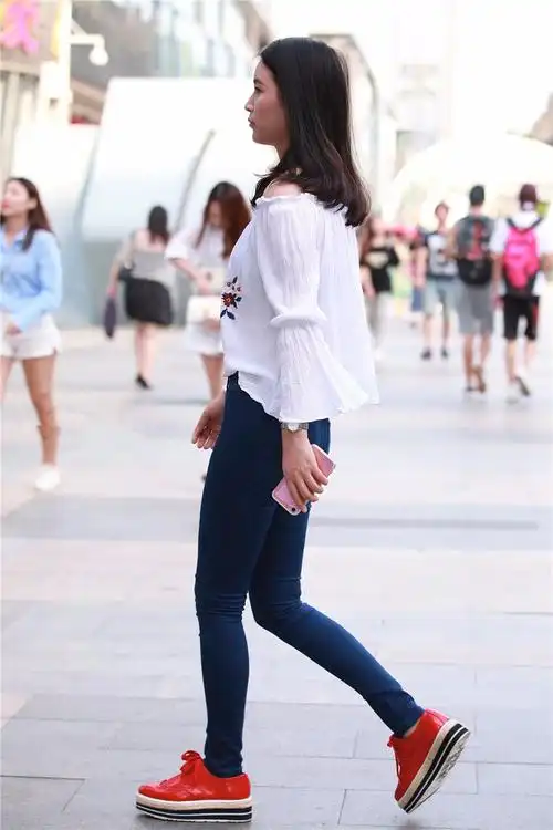 路人街拍穿着红色运动鞋的紧身牛仔裤美女身材比例十分匀称