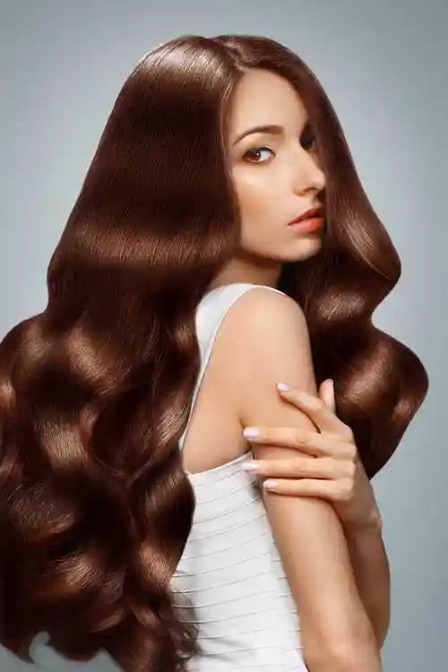 在演播室白色背景下的穿着红色衣服的美丽的长黑发女模特