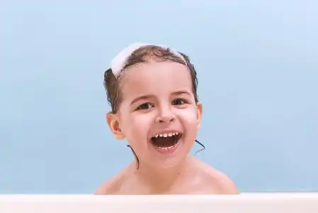 小孩子在浴缸里.微笑的孩子在浴室的蓝色背景.婴儿洗涤和沐浴.