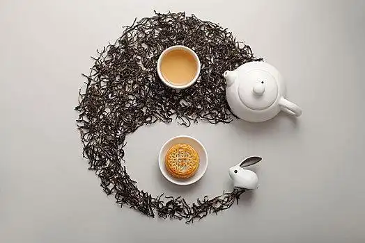 用茶叶铺设的太极图上摆放的月饼和茶杯