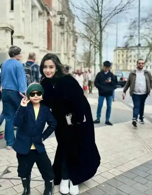 为了配合小男孩的身高,angelababy蹲下身子,面带淡淡的笑容,将手伸到