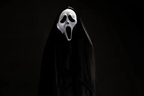 有人在黑色封面与白色幽灵面具角色扮演魔鬼表演爬可怕