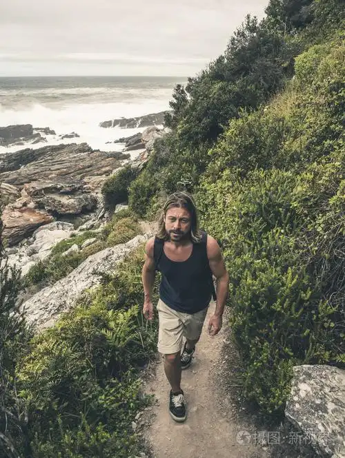 男性的徒步旅行者长长的金发,在齐齐卡马在道路上行走