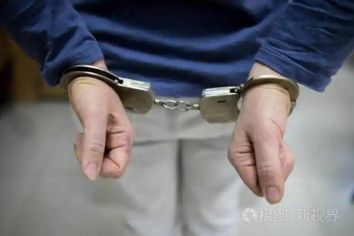 照片 特写镜头.被逮捕的男子双手铐在灰色背景上被隔离的背部.