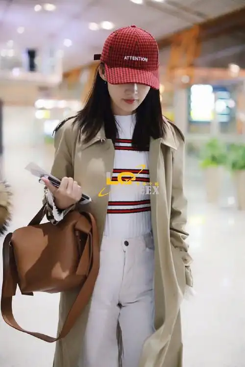 李沁戴红色棒球帽穿风衣搭配休闲裤现身机场,皮肤白皙面带微笑