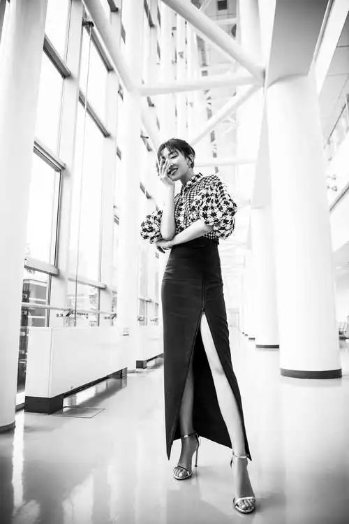 她扎着高马尾,身着黑白千鸟格上衣搭配黑色开叉裙,脚踩一字高跟鞋,展