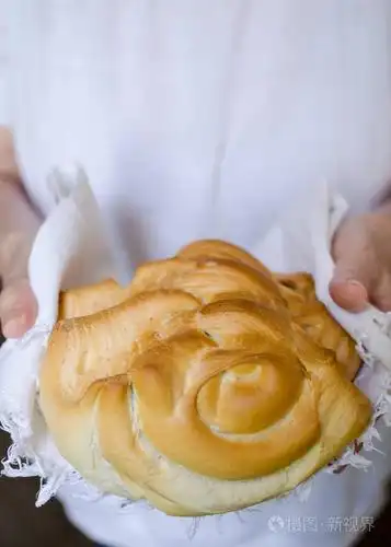 面包师拿着一个漂亮的新鲜烘焙的温暖面包. 乡村复古风格.