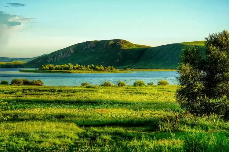 阳光照耀下的草地和绿水青山