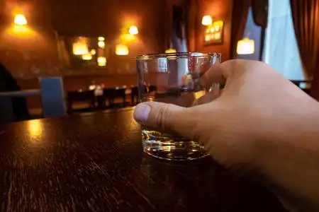 在一家酒吧里,一个男人手拿着金黄色的酒精饮料.下班后放松,喝酒照片