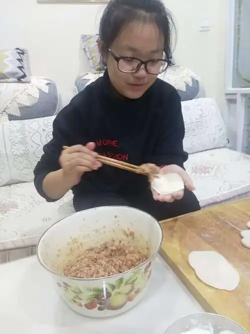 开始包饺子了,我一个手拿饺子皮,一个手拿夹着饺子馅的筷子.