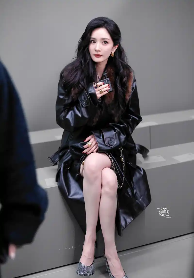 杨幂身穿绒毛领黑皮大衣,脚踩银色高跟鞋,戴着墨镜,搭配大波浪卷发