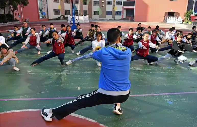 李向阳(前)带领学生们在体育课上热身(11月13日摄).