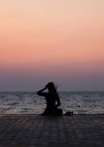 一个女孩在日落背景(日出)上的剪影在海平线上. 夏天在海滩上散步.