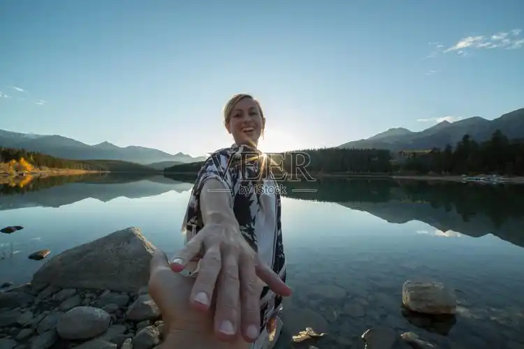 夕阳西下时欢快的情侣在湖边手拉手照片摄影图片