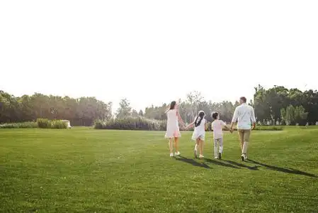 一家四口手牵手在公园户外共度周末的场景照片