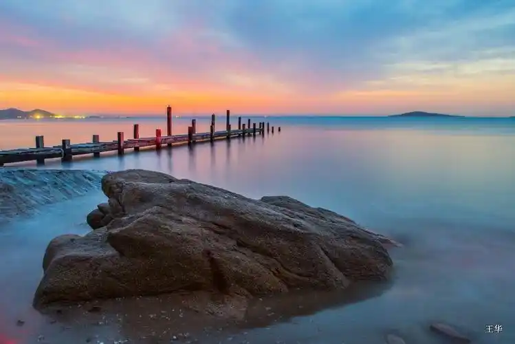 青岛崂山会场海边断桥与美丽的日出朝霞相映成趣