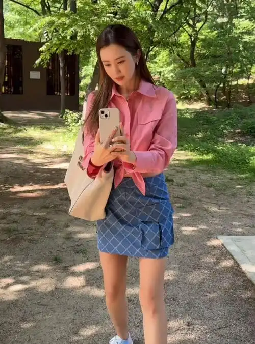 照片中的李多海身穿粉色格子衬衫,搭配牛仔口袋格子迷你裙,展现出清纯