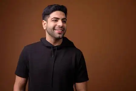 年轻英俊的印度人反对棕色背景照片