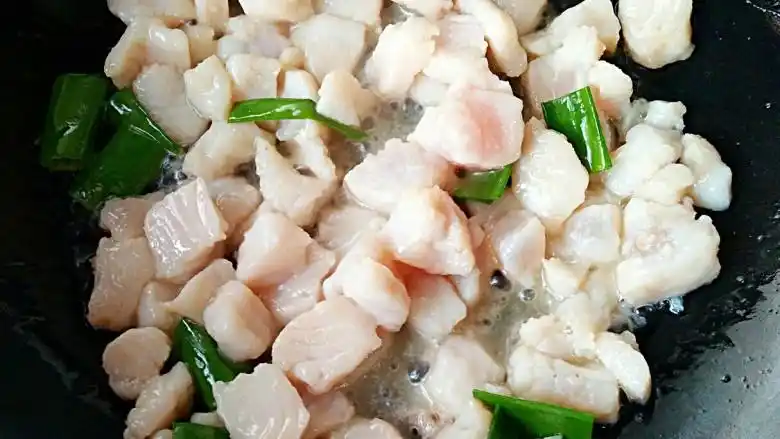 鱼米之乡,锅中倒入适量油烧至7成热,下葱段爆香,倒入腌制好的鱼肉丁