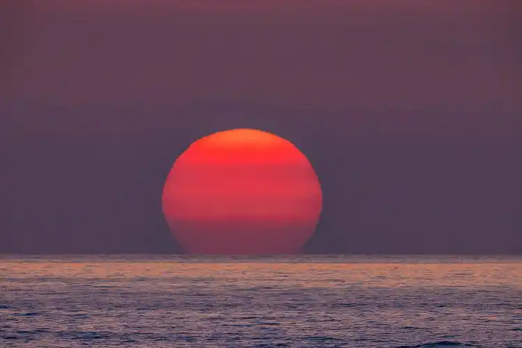日出时巨大的太阳从海上升起图片下载