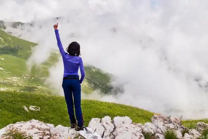 年轻女人站在悬崖的边缘和与举的手向天空看