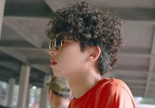 男生斜刘海自然卷短发烫发发型,鬓角的头发做的要稍微长一些,空气感