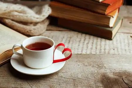 木桌上的一叠书,折纸工艺一杯茶的形状. 图书馆教育休闲时间概念.