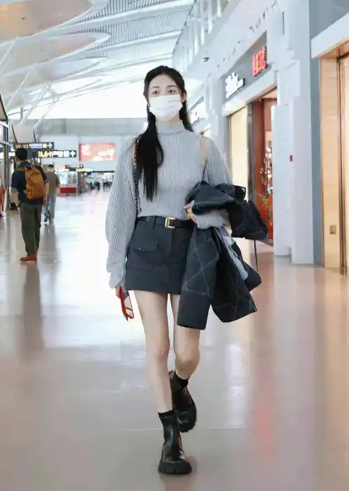 周洁琼现身机场,穿着一件灰色的针织毛衣,搭配了黑色半身裙,温柔又很
