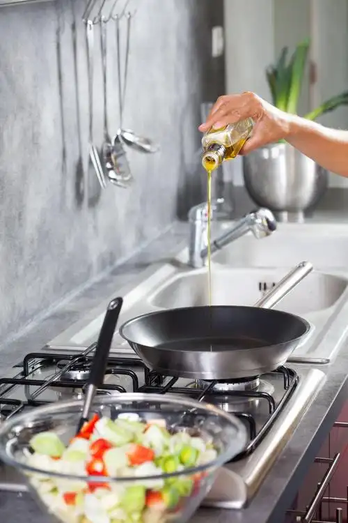 厨房里厨师正在往锅里倒油