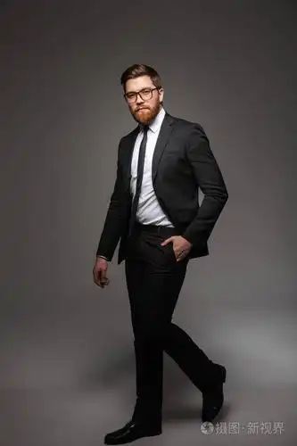 一个充满自信的年轻商人穿着西装走在灰色背景下行走的全长肖像