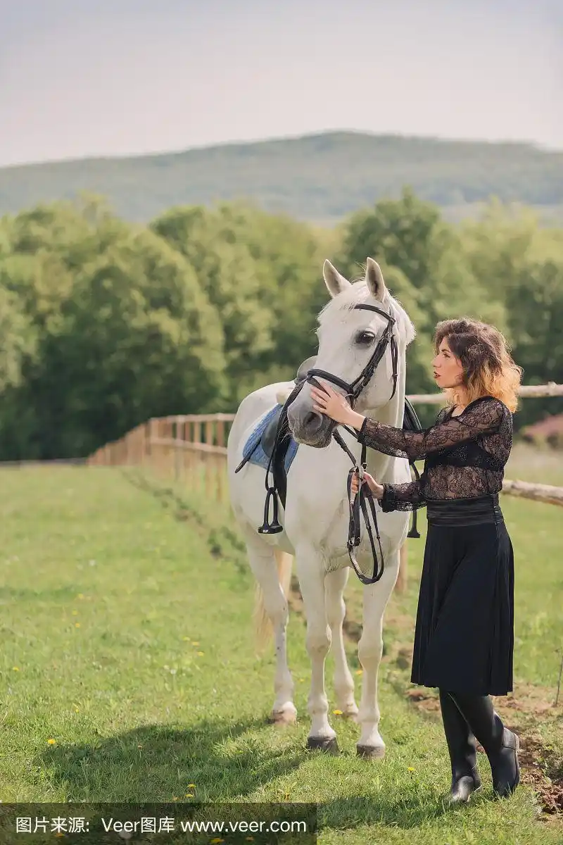 穿着黑衣的年轻女子骑着白马在户外