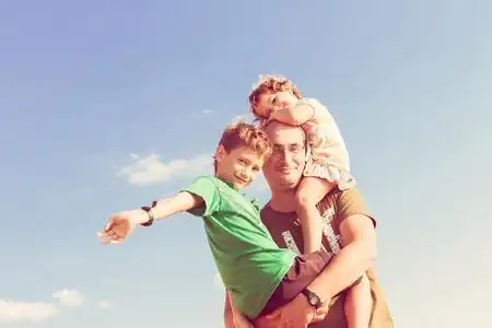 快乐的父亲和两个孩子在户外玩微笑着快乐的母亲和小儿子一起在公园里