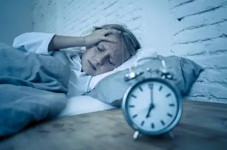 夜醒甜蜜的失眠小女孩躺在床上悲伤地看着闹钟,不得不醒来,但在烦恼中