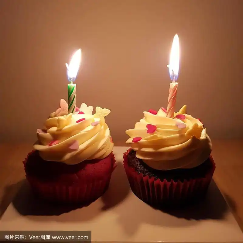 烛光下的两个纸杯蛋糕