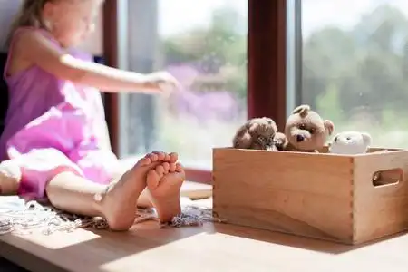 孩子赤脚坐在家里的窗台上.孩子正往窗外看.