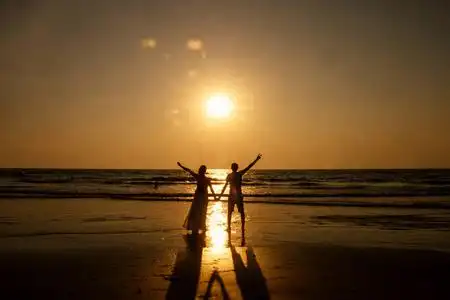 美丽的情侣漫步在海滩上夕阳沙滩上漫步的浪漫幸福夫妻两个情人在夕阳