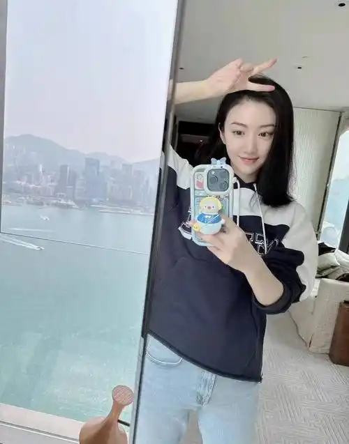 身穿蓝白连帽毛衣,直筒牛仔裤的景甜对着镜子来了一张甜蜜的自拍照