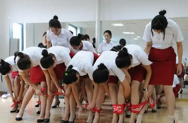 图为一些礼仪小姐在训练站姿,双腿夹着纸片站立是最常见的训练方法.