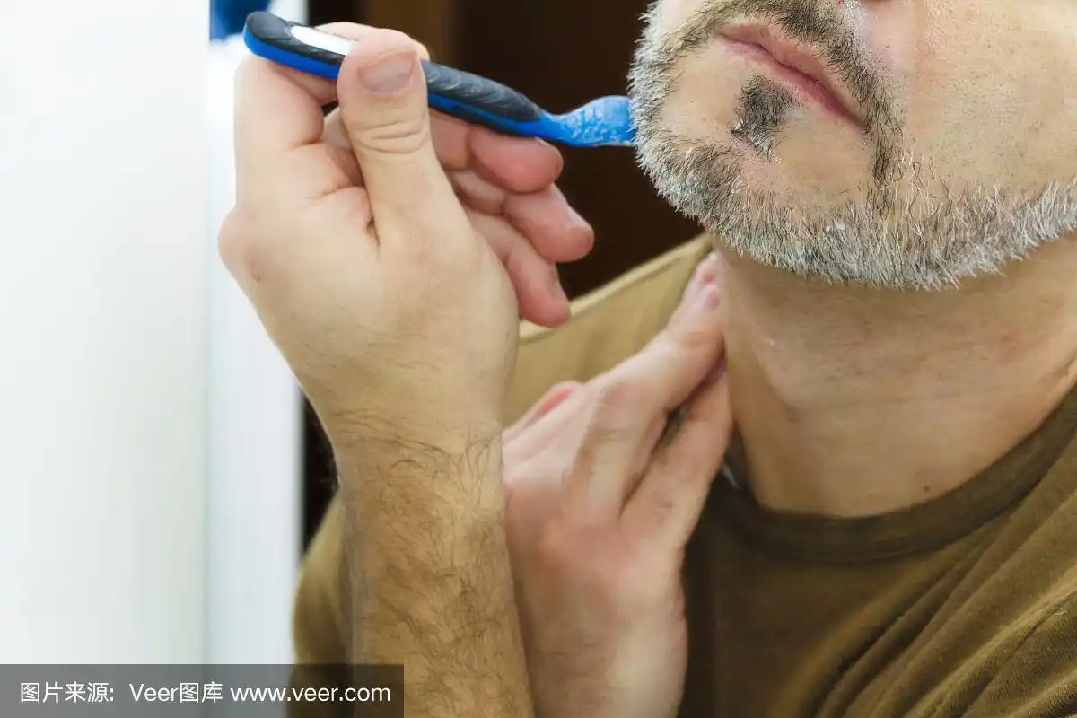 一个成年男子用剃刀刮胡子的特写