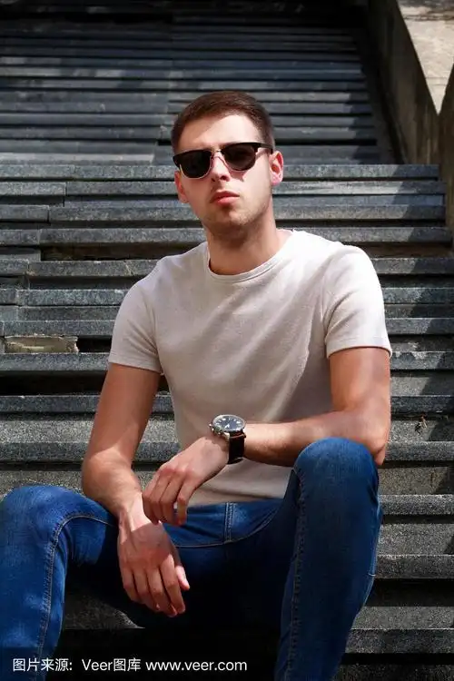 一个人独自坐在台阶上.戴墨镜的帅哥.男模特正摆姿势拍照,坐在旧楼梯