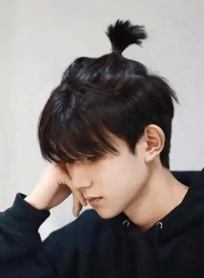 易烊千玺坐在行李箱中盘着腿,这个方式挺特别的,在头发上面梳着小揪揪