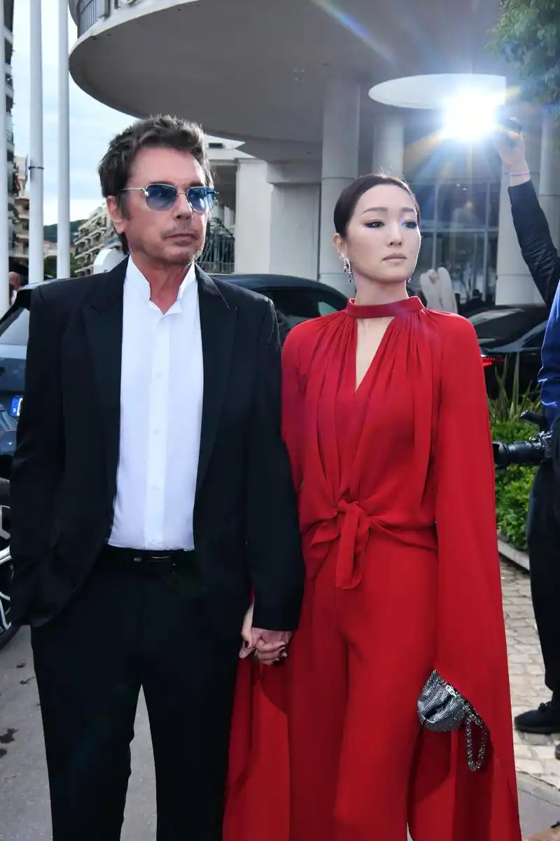 巩俐身穿红色裤装,牵手丈夫让-米歇尔·雅尔出席戛纳首映红毯