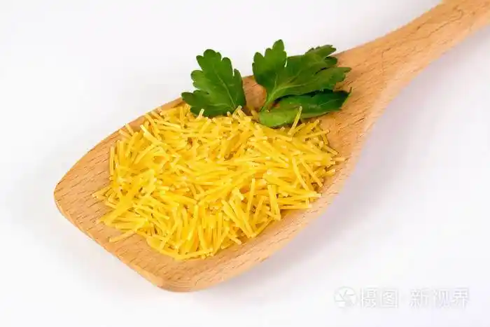 白色背景的木勺上放着欧芹的生粉丝