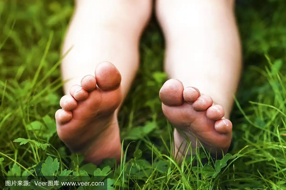 小女孩的脚在绿色的草地上的特写