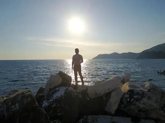 站在夕阳下岸边的礁石上眺望傍晚的海平面