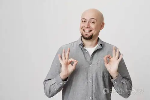 开朗和迷人的光头男子与胡子显示好或罚款标志与双手, 而微笑明亮的