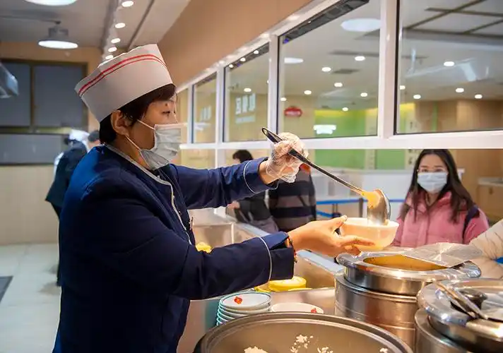 11月12日,山西省太原市迎泽区南官坊社区食堂的工作人员在为市民打饭.